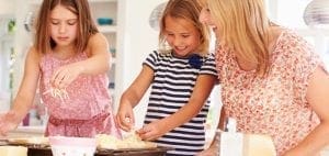 Mother and two daughters prepare food in a kitchen.