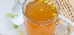 Broth in a mug with chopped green onions.