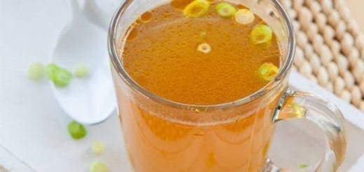 Broth in a mug with chopped green onions.