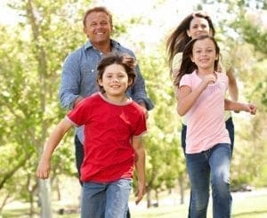 Family jogging together in a park on a sunny day.
