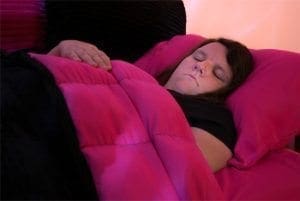 Woman sleeping under a pink blanket.