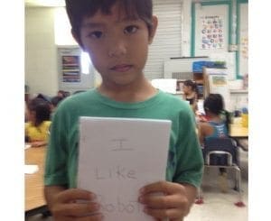 Leandro holds up a book he made with drawings of robots.