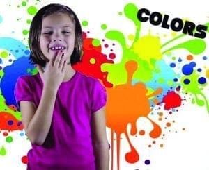 A young girl smiles in front of a colorful paint splatter background with the word "COLORS" at the top.
