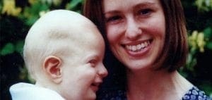 A woman smiles while holding a baby.