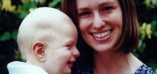 A woman smiles while holding a baby.
