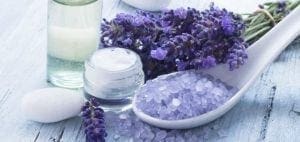 Lavender bath salts, cream, and oil on a wooden surface.