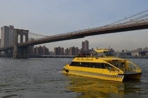 Yellow water taxi passes under the Brooklyn Bridge.