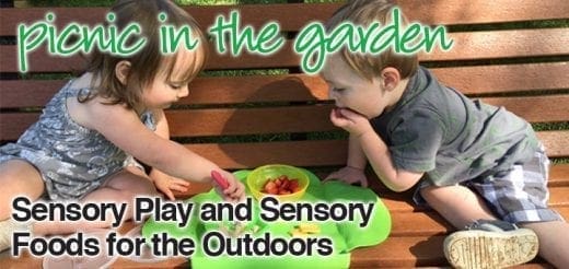 Two young children play with sensory toys and food on a picnic blanket.