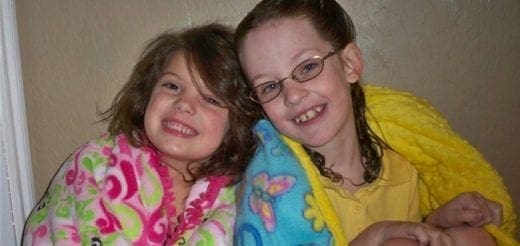 Two young girls smiling while wrapped in blankets.
