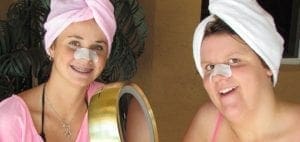 Two women with towels on their heads and nose strips smiling.