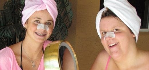Two women with towels on their heads and nose strips smiling.