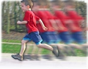 A young boy in a red shirt and blue shorts runs, with motion blur indicating speed.