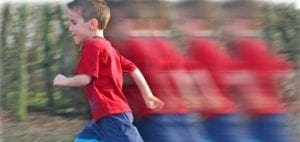 A young boy in a red shirt runs with motion blur, appearing multiple times.