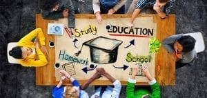 Students around a table with a drawing of a graduation cap and words like "Study," "Education," "Homework," and "School.