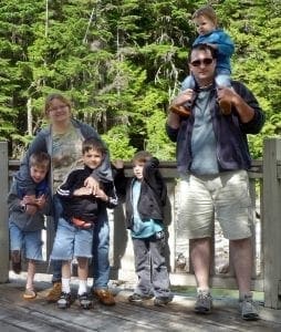 The Corwin Hall family posing on a boardwalk with trees in the background.