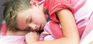 Young child sleeping soundly with head resting on arms.