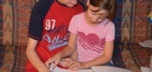 Two children sitting together on a couch.