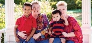 Two women and two young boys sit together outdoors.