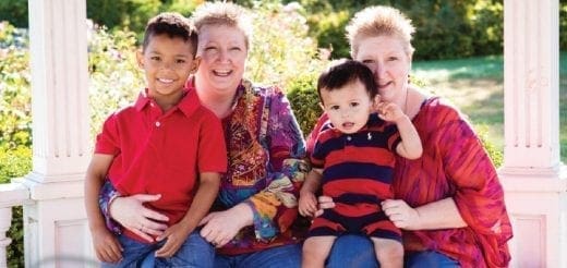 Two women and two young boys sit together outdoors.