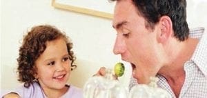 A father offers a piece of food to his daughter.