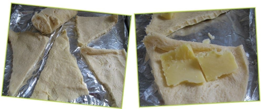 Croissant dough triangles on a baking sheet, with cheese slices on some of them