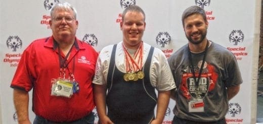 Three men stand in front of a Special Olympics banner.