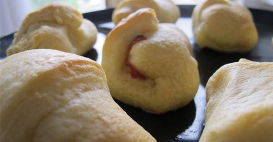 Ham and cheese croissants on a black plate.