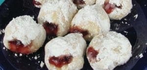 Sufganiyot dusted with powdered sugar and filled with jelly.