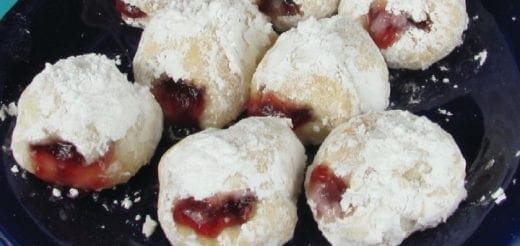 Sufganiyot dusted with powdered sugar and filled with jelly.