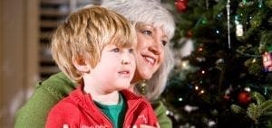 A boy and a woman look at a Christmas tree.