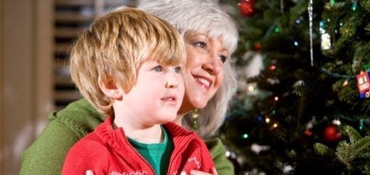 A boy and a woman look at a Christmas tree.