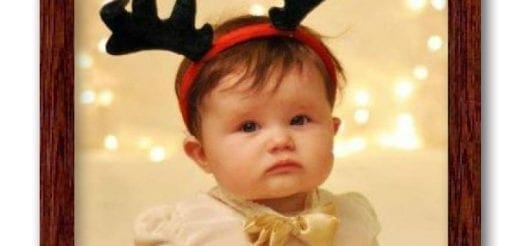 Baby wearing a reindeer headband with a grumpy expression.