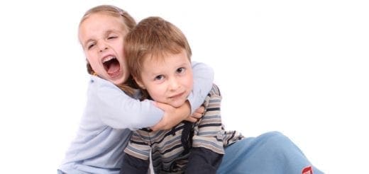 A girl hugs a boy from behind, pulling his shirt.