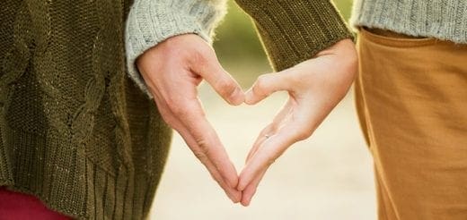 Two people's hands form a heart shape.