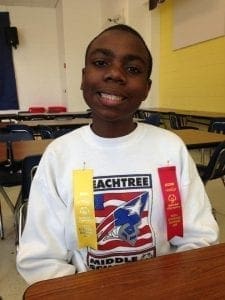 Benjamin smiling with two award ribbons pinned to his shirt.