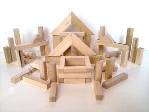 Wooden building blocks arranged in various structures on a white surface.