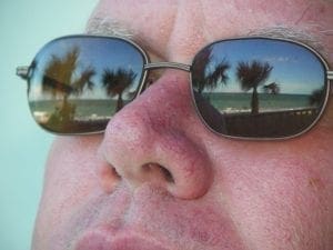Palm trees reflected in sunglasses worn by a person.