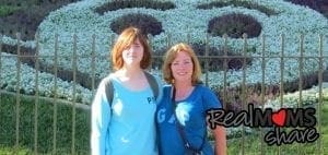 Mitzi McGilvray and her daughter Caitlyn pose in front of a floral display.