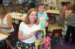 Mitzi McGilvray and her daughter Caitlyn smiling and holding a drawing.