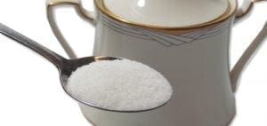 Spoonful of sugar next to a sugar bowl