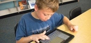 Boy using a tablet computer with a keyboard attachment.