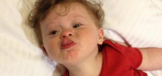 Baby sticking out tongue in red shirt