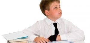 Boy in white shirt and tie at a desk with books