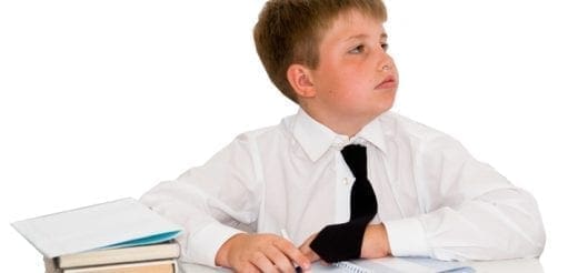 Boy in white shirt and tie at a desk with books