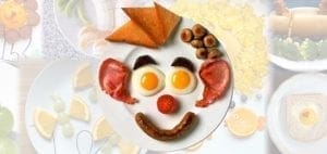 A plate of breakfast food arranged to resemble a clown face.