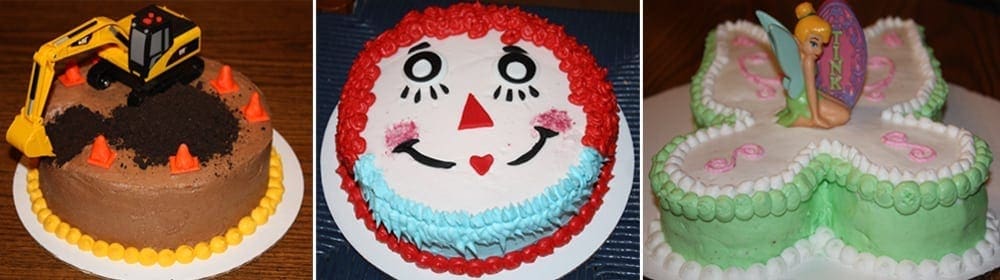 Three decorated cakes: one construction-themed, one rag doll face, and one butterfly with a fairy figurine.