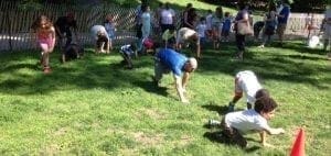 Children and adults participate in an outdoor activity on a grassy field.