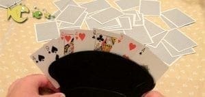 Playing cards held in a black card holder with a pile of cards in the background.