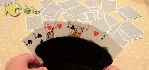 Playing cards held in a black card holder with a pile of cards in the background.