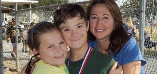 A woman and two children smile for a photo at an outdoor event.